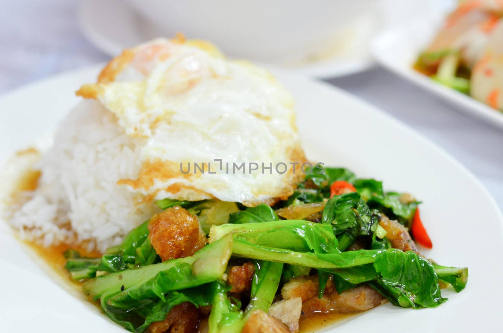 Stir-fried kale  with crispy pork and fried egg on  rice 
