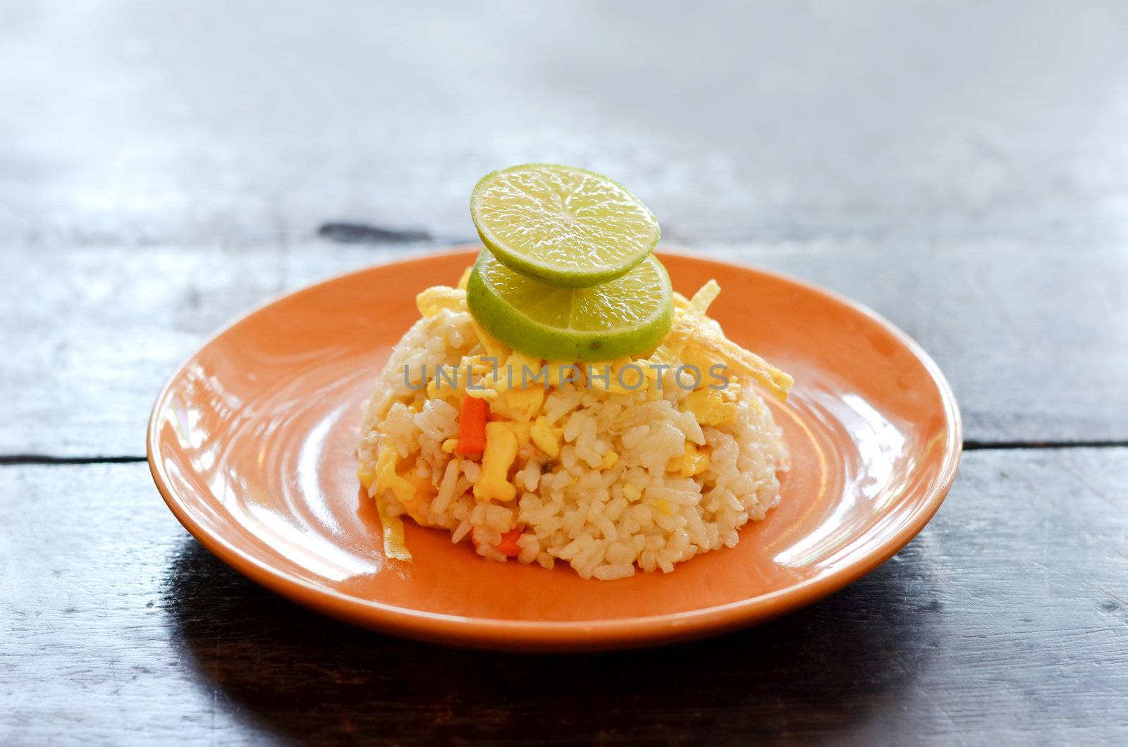  fried rice served with omelet  slice and lemon slice , on wood table