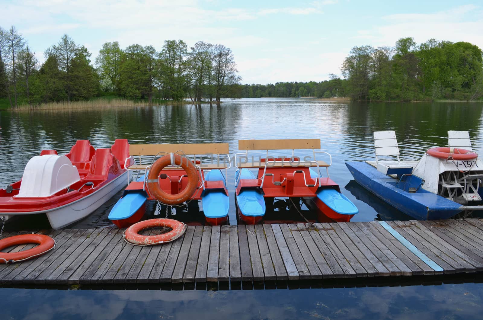 Different water bicycles locked at lake harbor and rescue circles. Active recreation objects equipment.