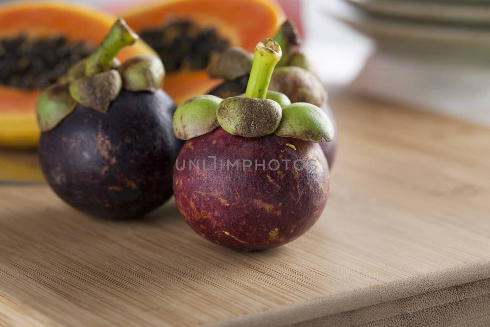 Three fresh tropical mangosteen on cutting board