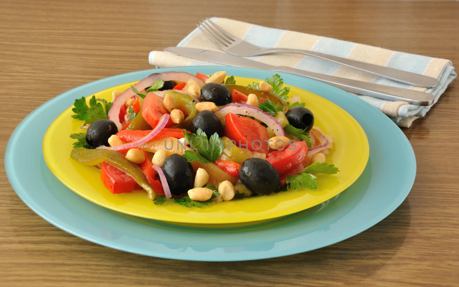Salad of roasted peppers with tomato, peanuts and olives, onions and greens 