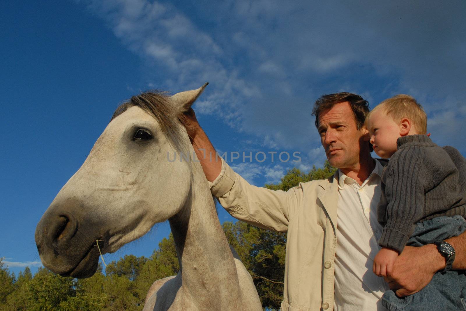 a father and his son stroking a gray horse