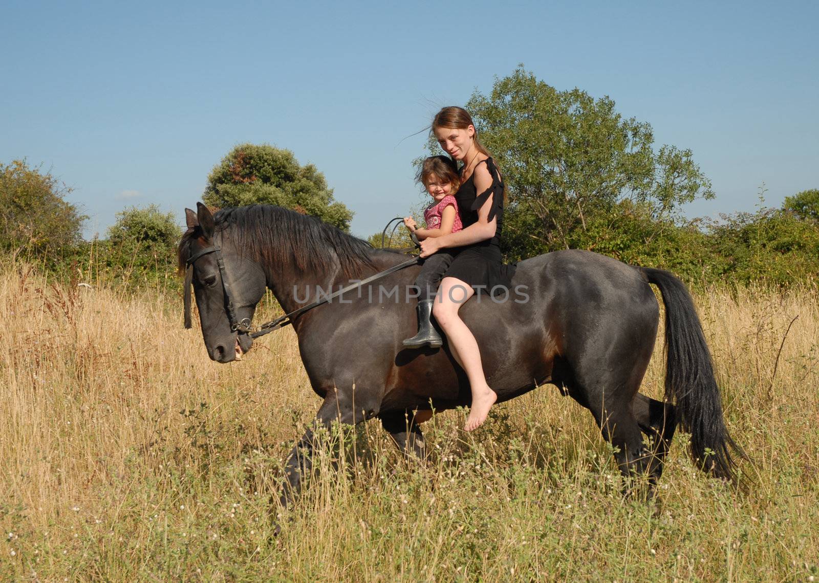 mother and her little daughter on a black stallion
