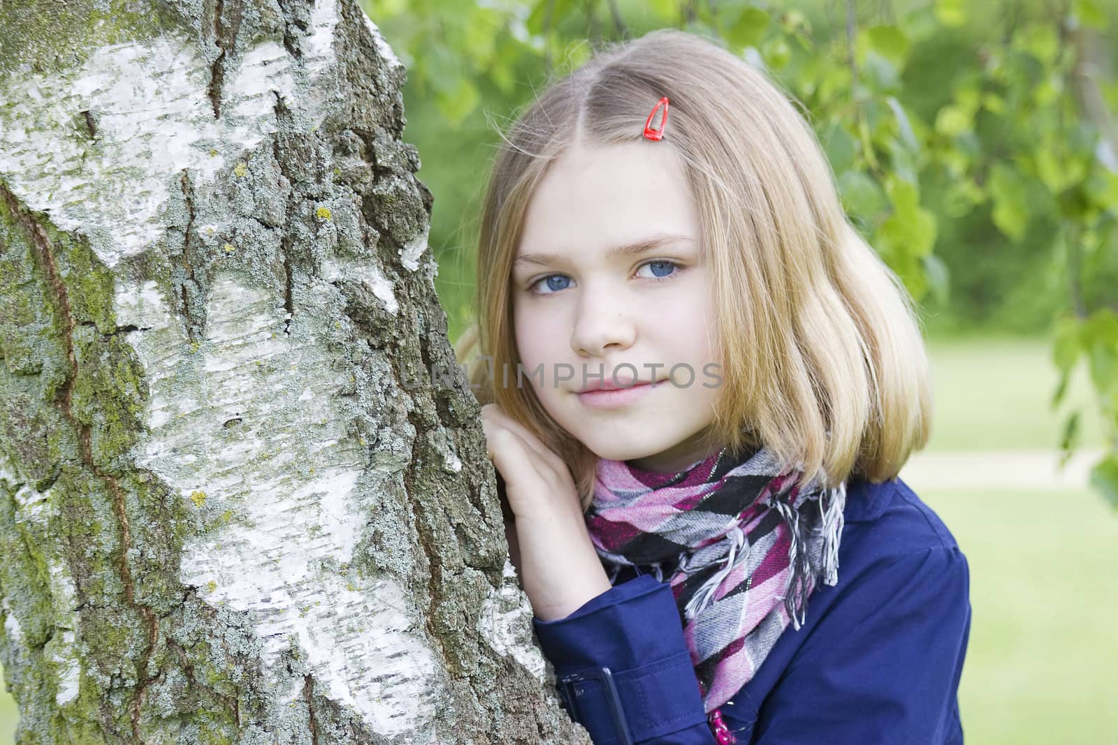 Portrait of young girl standing near birch tree at summer green park