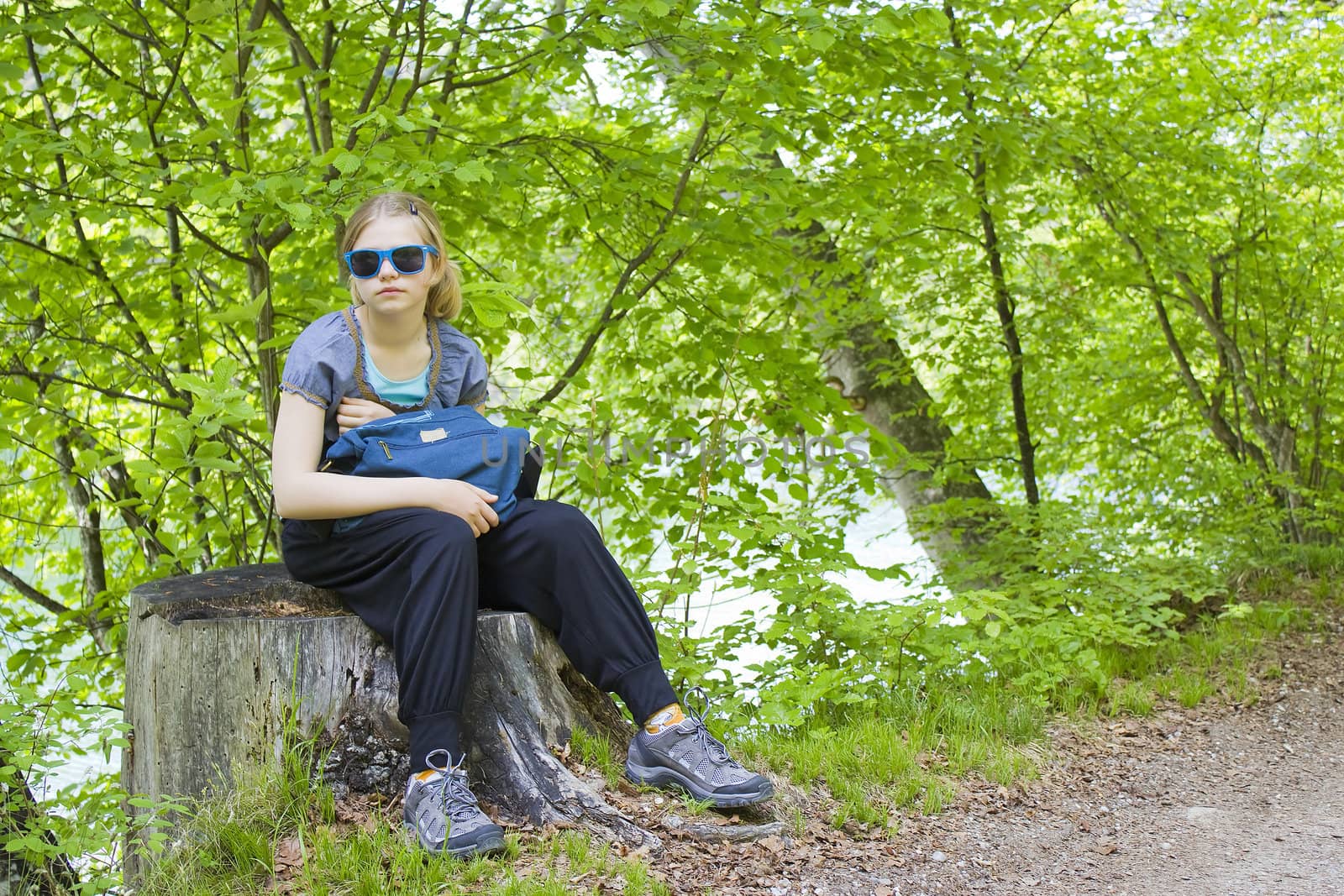 little girl sitting on a stump in the forest 