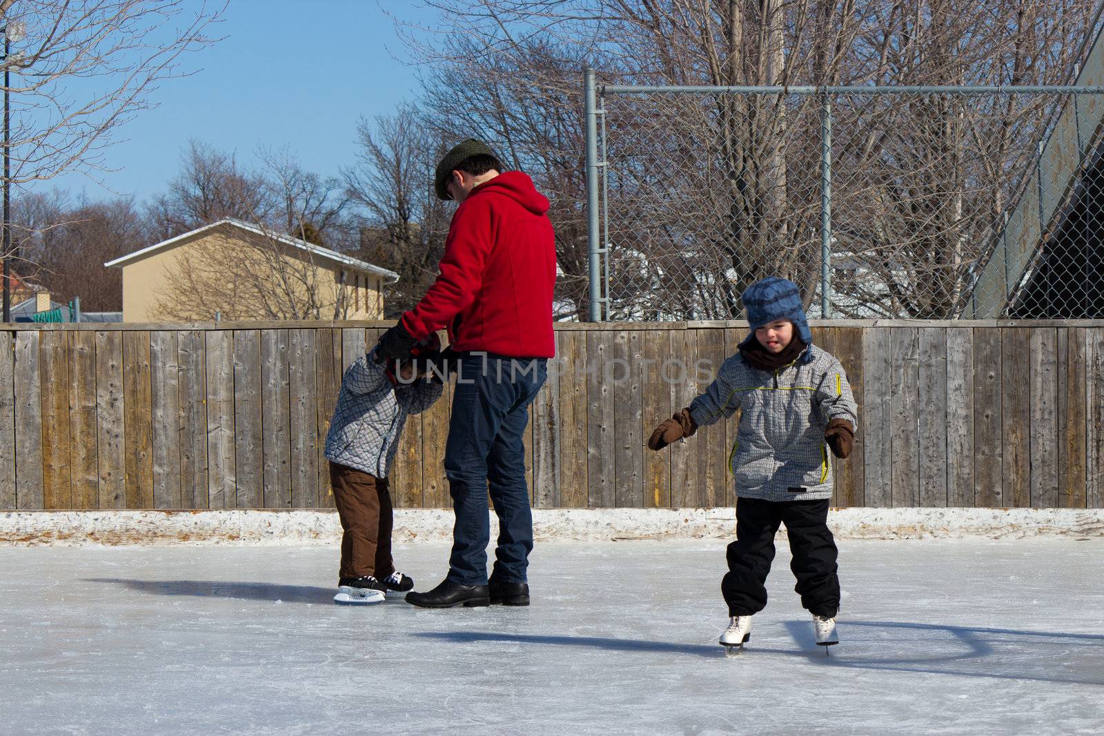 Father with son and daughter playing at the skating rink in winter.