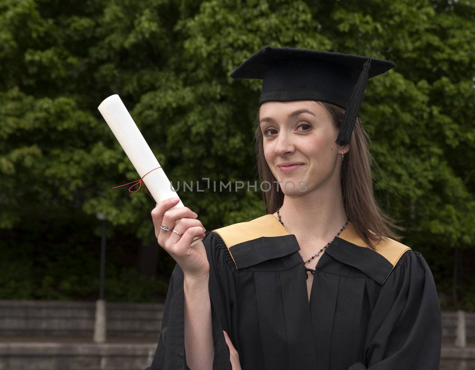 Young woman shows off certificate on graduation day.