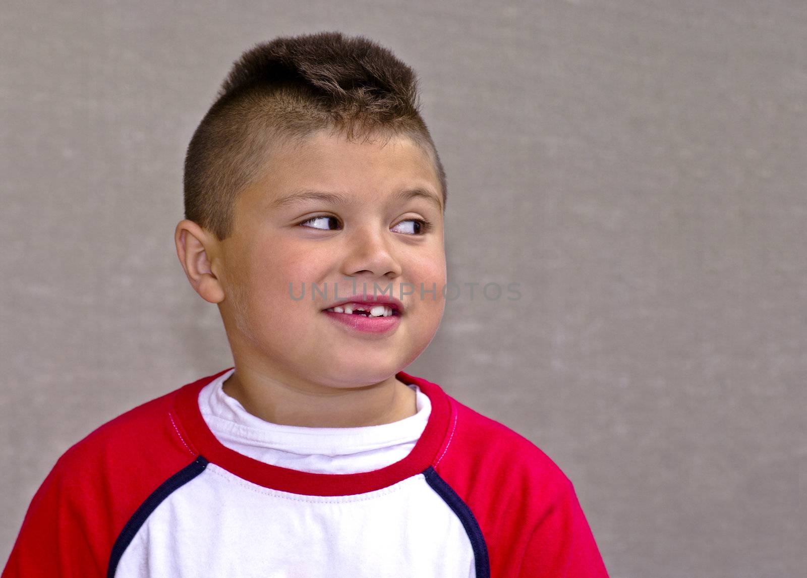 Young native boy with missing tooth looking sideways mischeviously.
