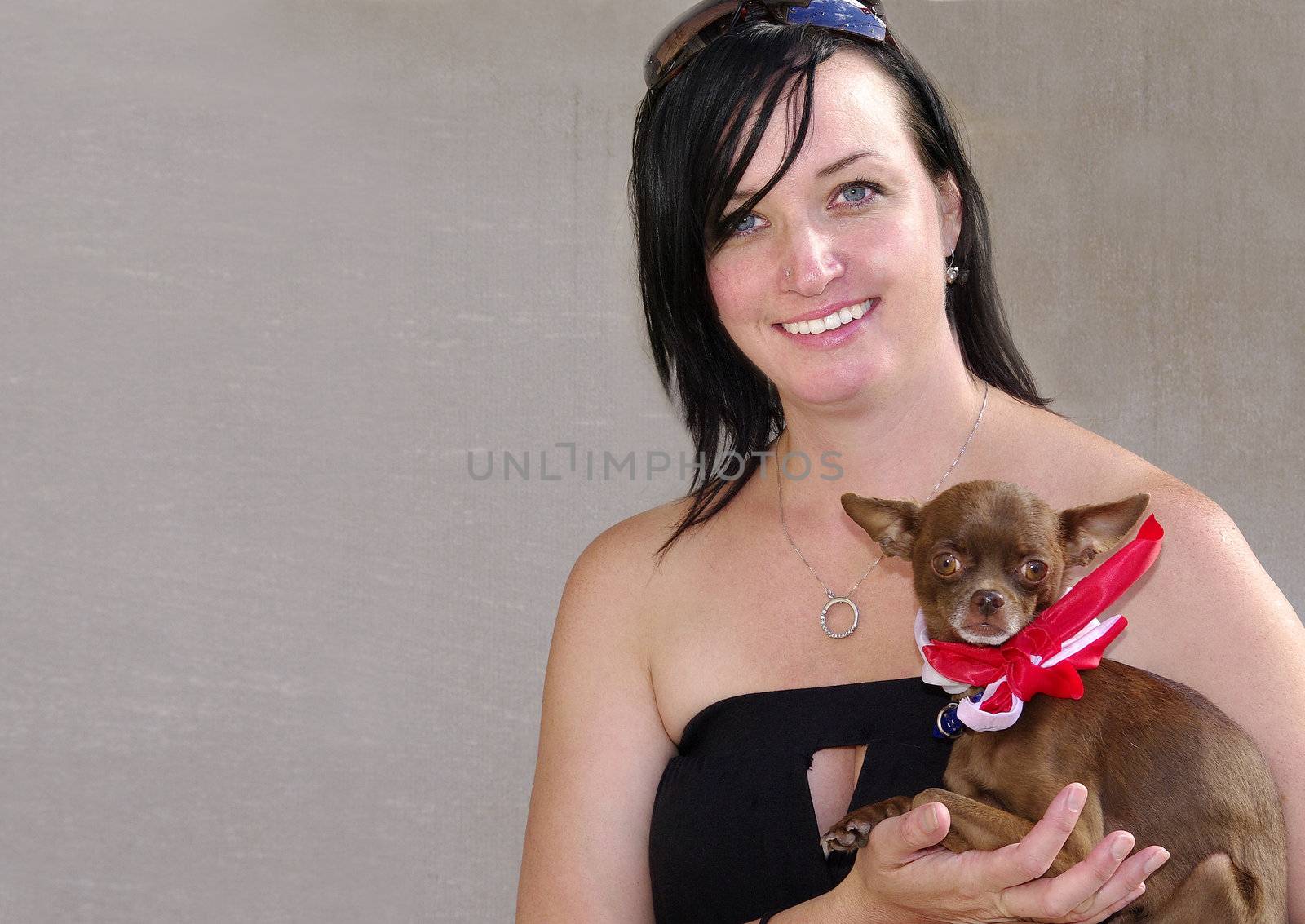 Young woman holding her pet chihuahua wearing a red and white scarf.
