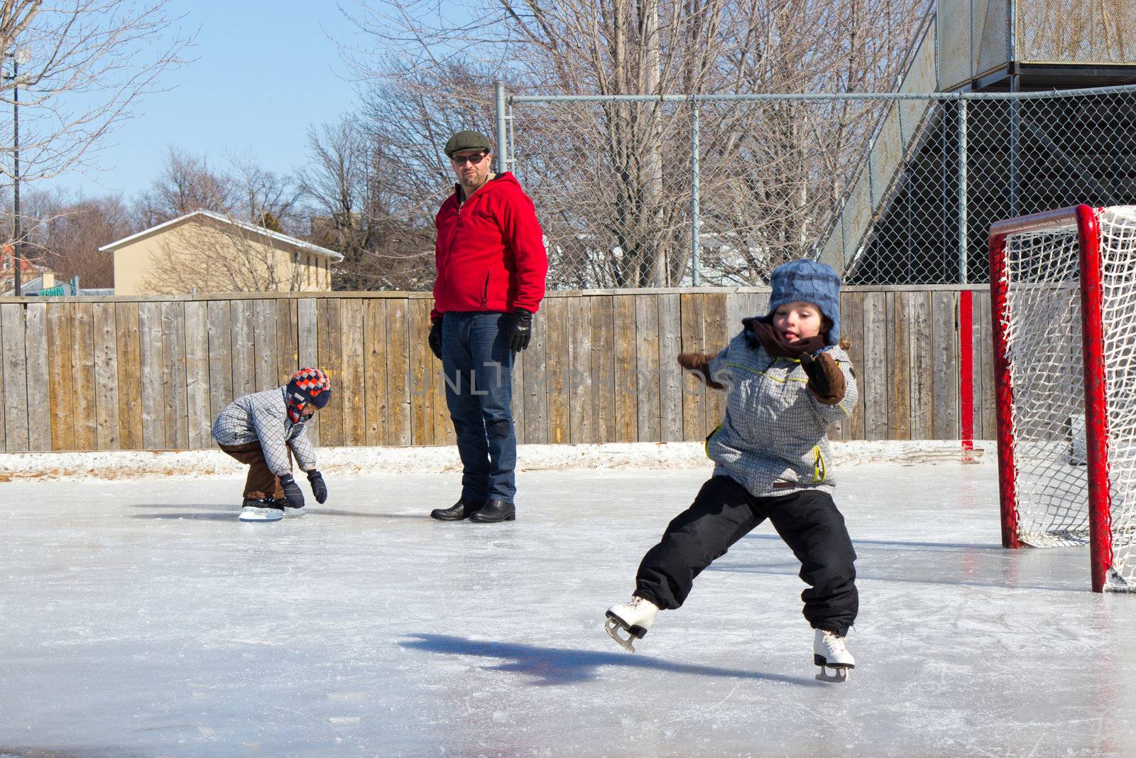 Father with son and daughter playing at the skating rink in winter.