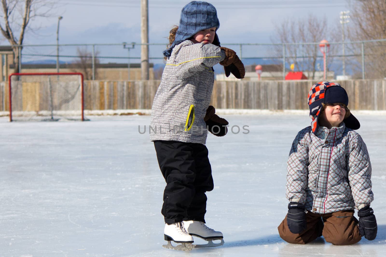 Children playing and skating at the outdoor skating rink during winter.