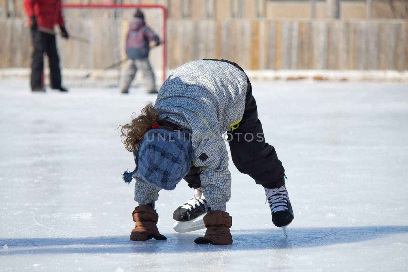 Child playing and skating at the outdoor skating rink in winter.