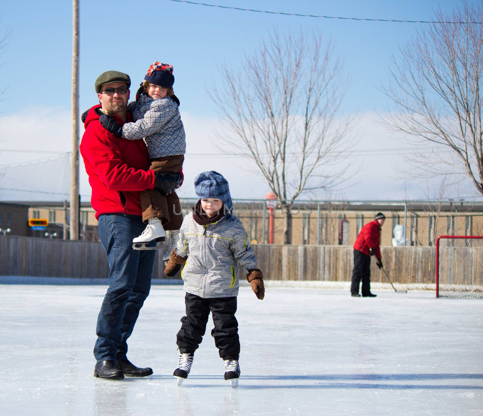 Father with son and daughter playing at the skating rink in winter.