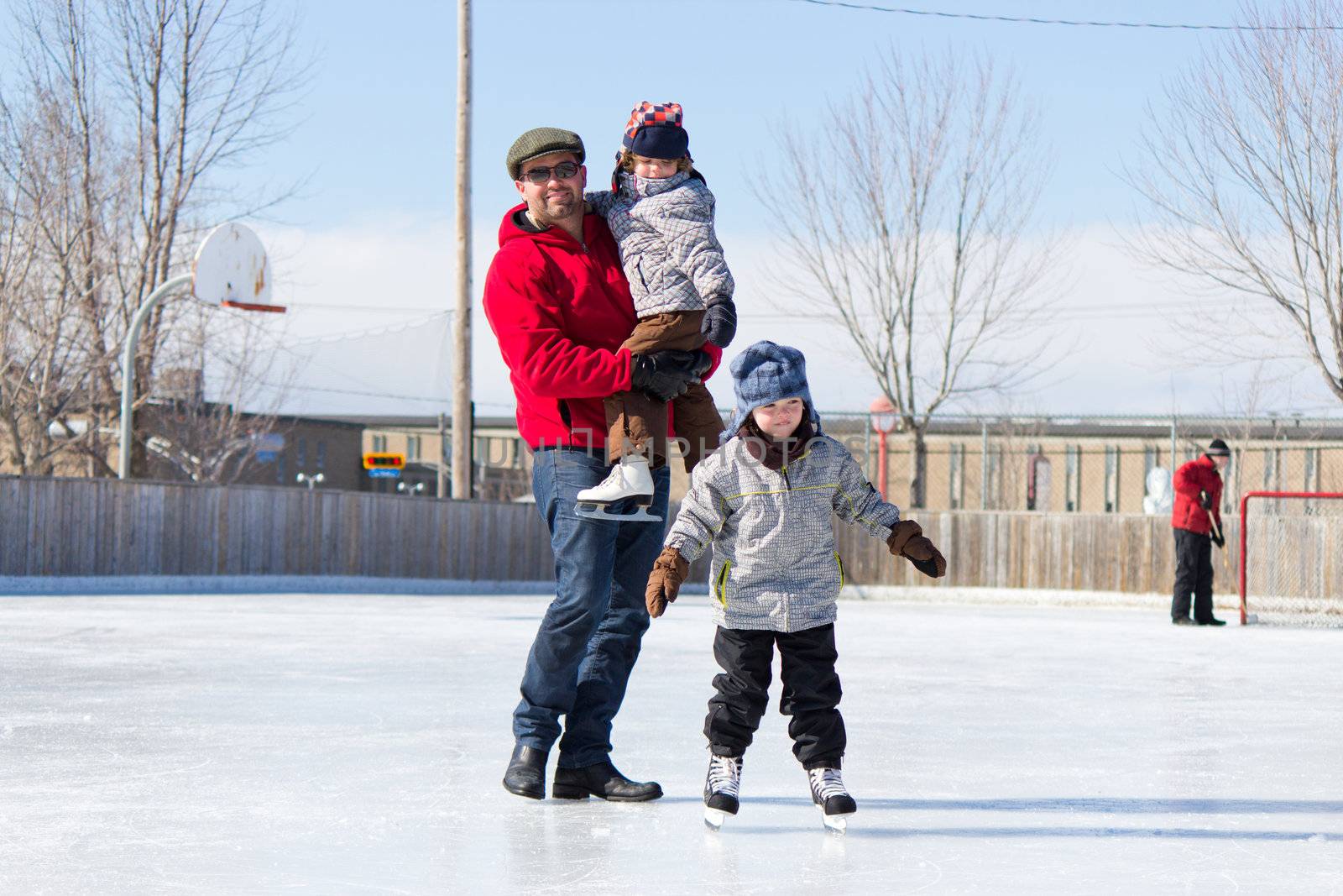 Father with son and daughter playing at the skating rink in winter.