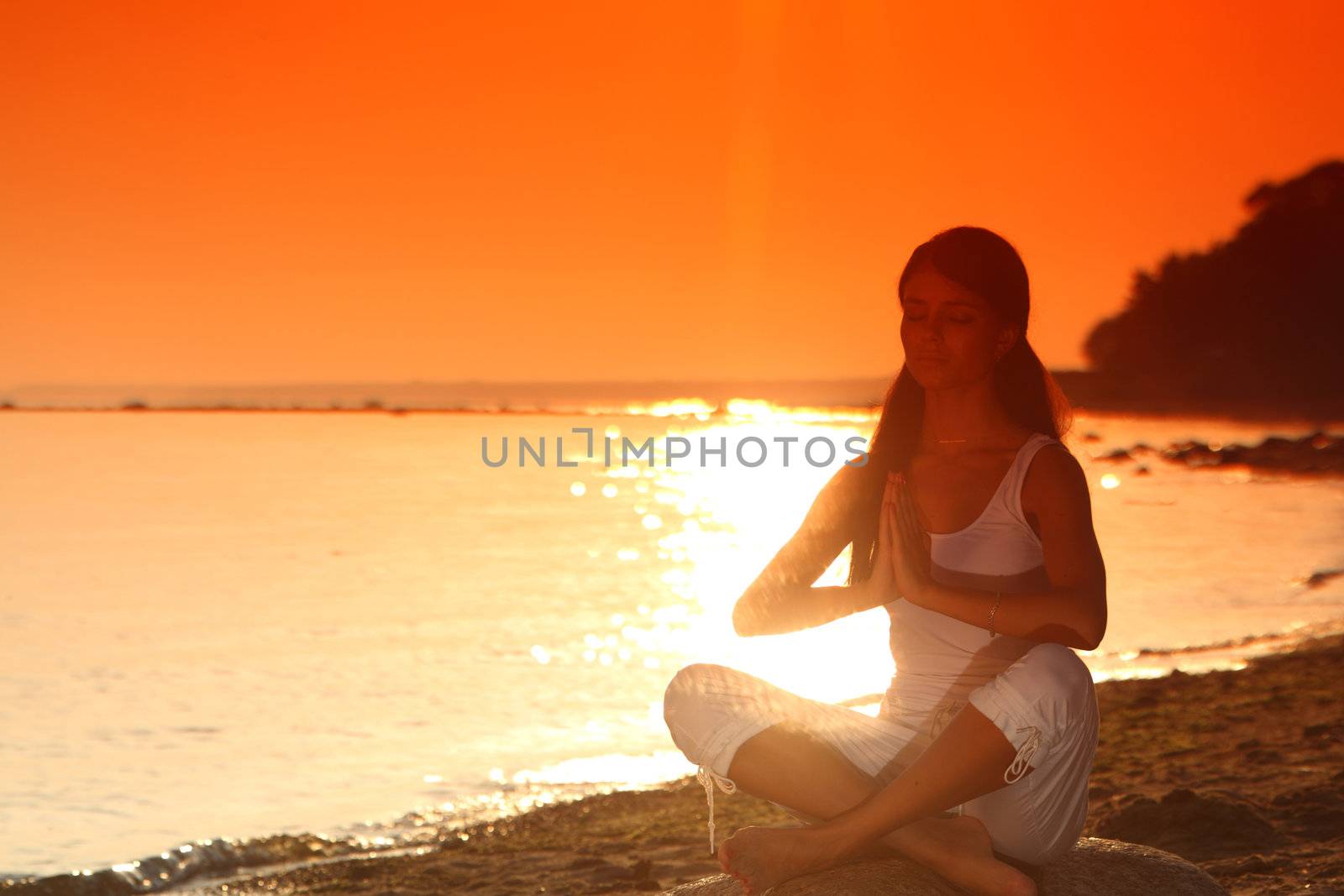 Young woman practicing yoga  near the ocean