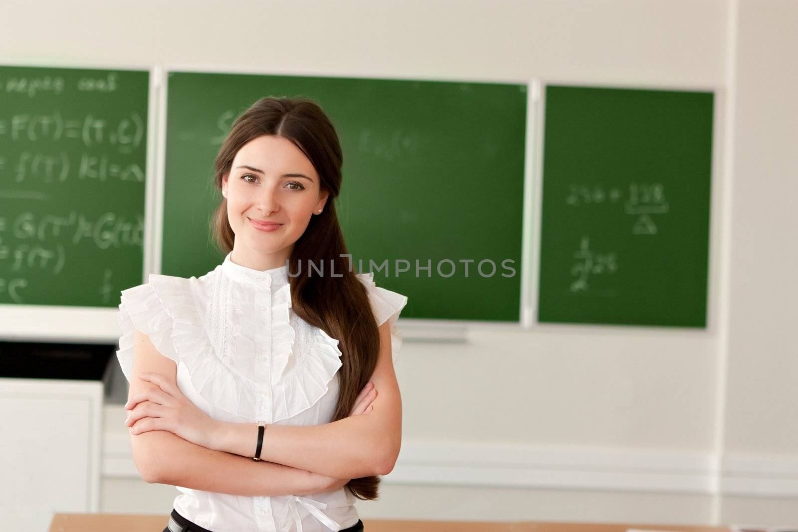 The teacher in the classroom on blackboard background.