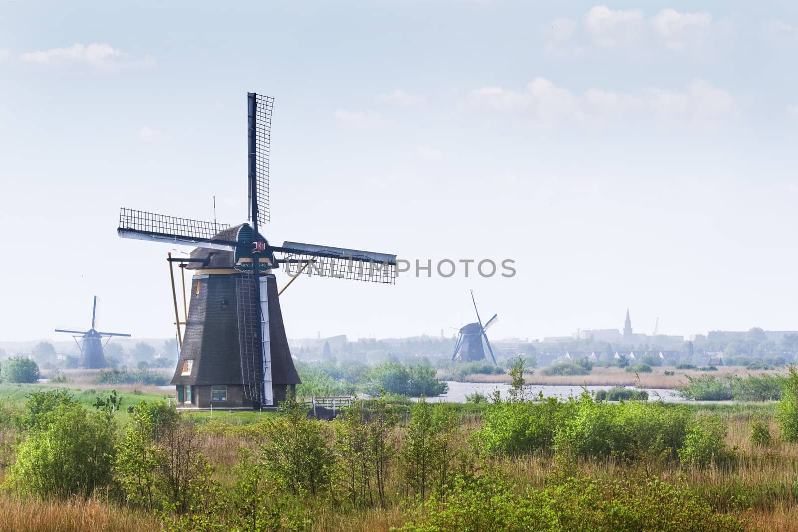 Country landscape with windmills at Kinderdijk, the Netherlands on hazy day in spring