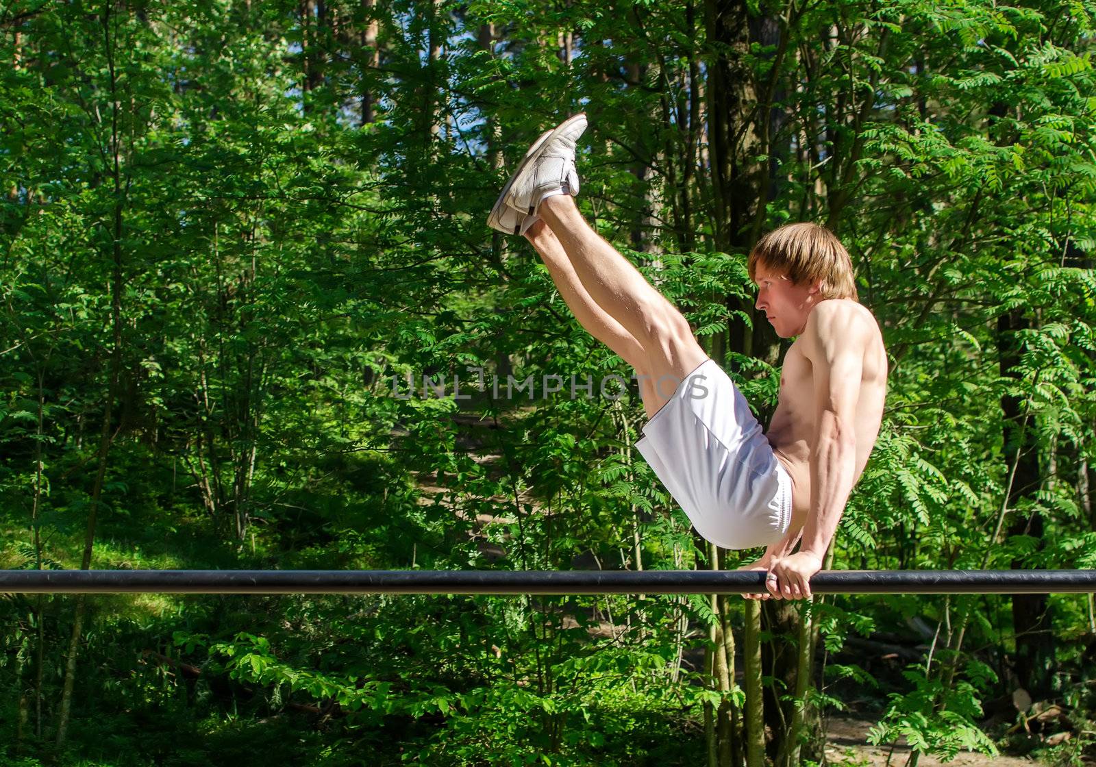 Attractive man pull-ups on a bar in a forest