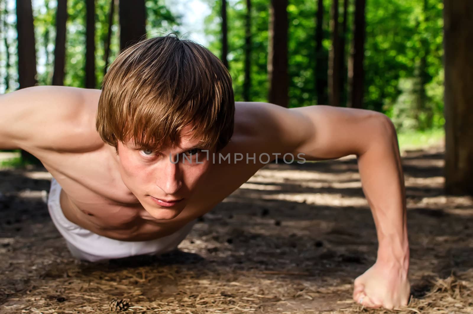 Attractive man doing a push up in forest