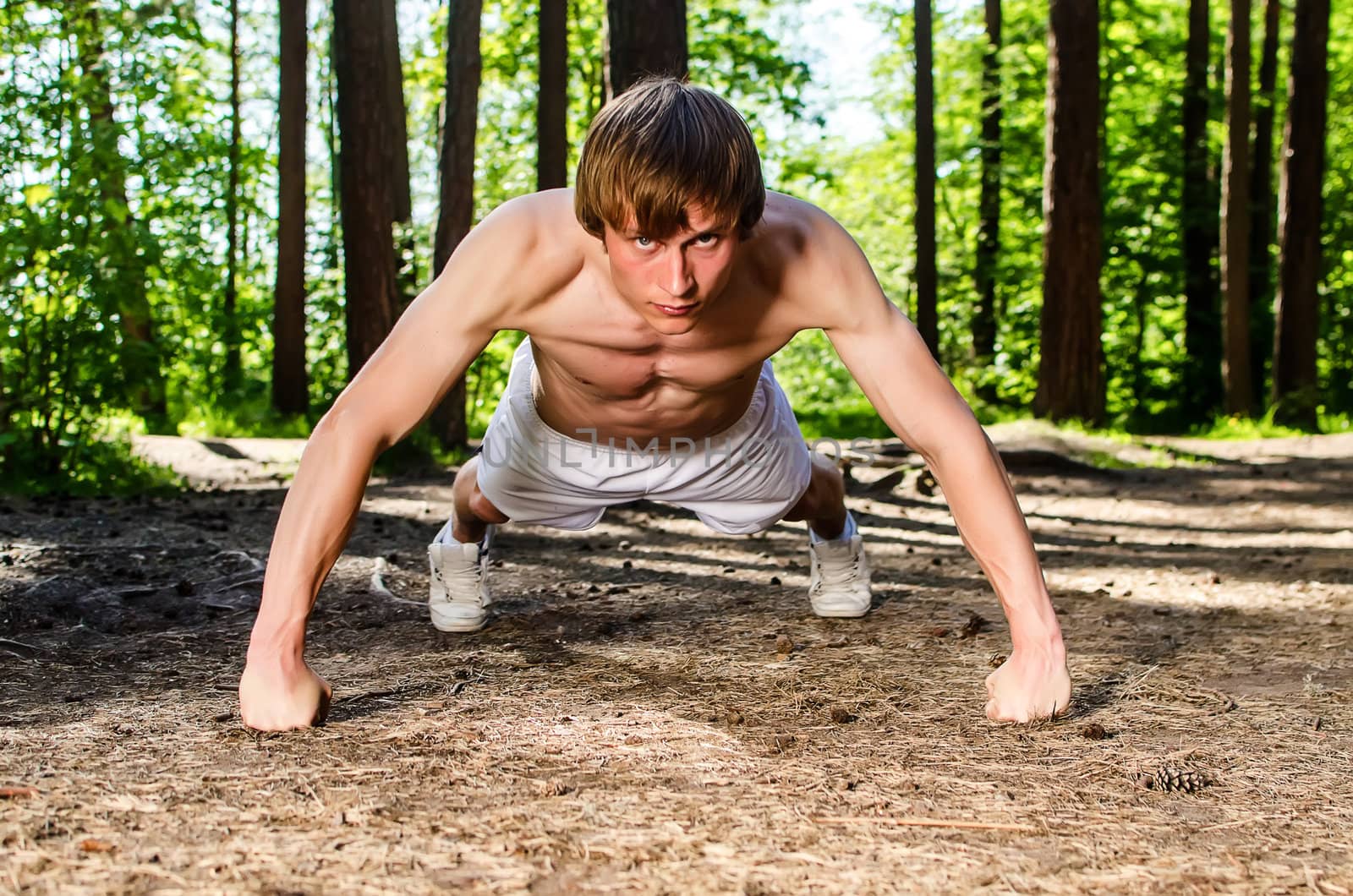 Attractive man doing a push up in forest