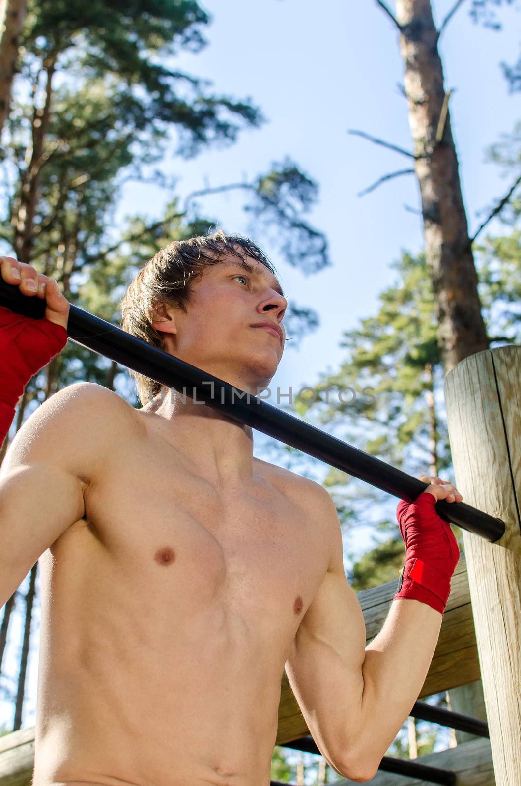 Attractive man pull-ups on a bar in a forest