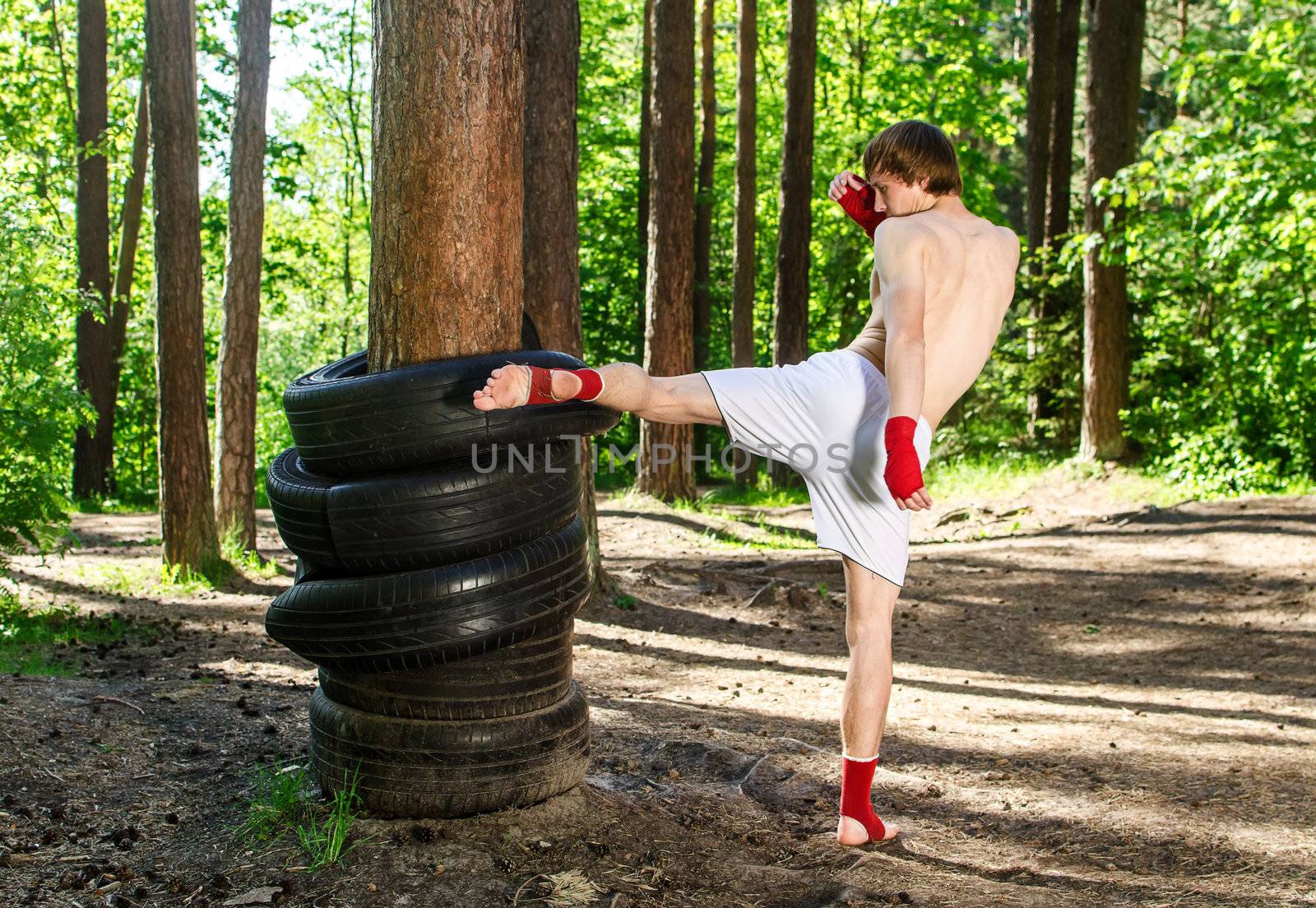 Fighter kicking rubber wheels with the leg