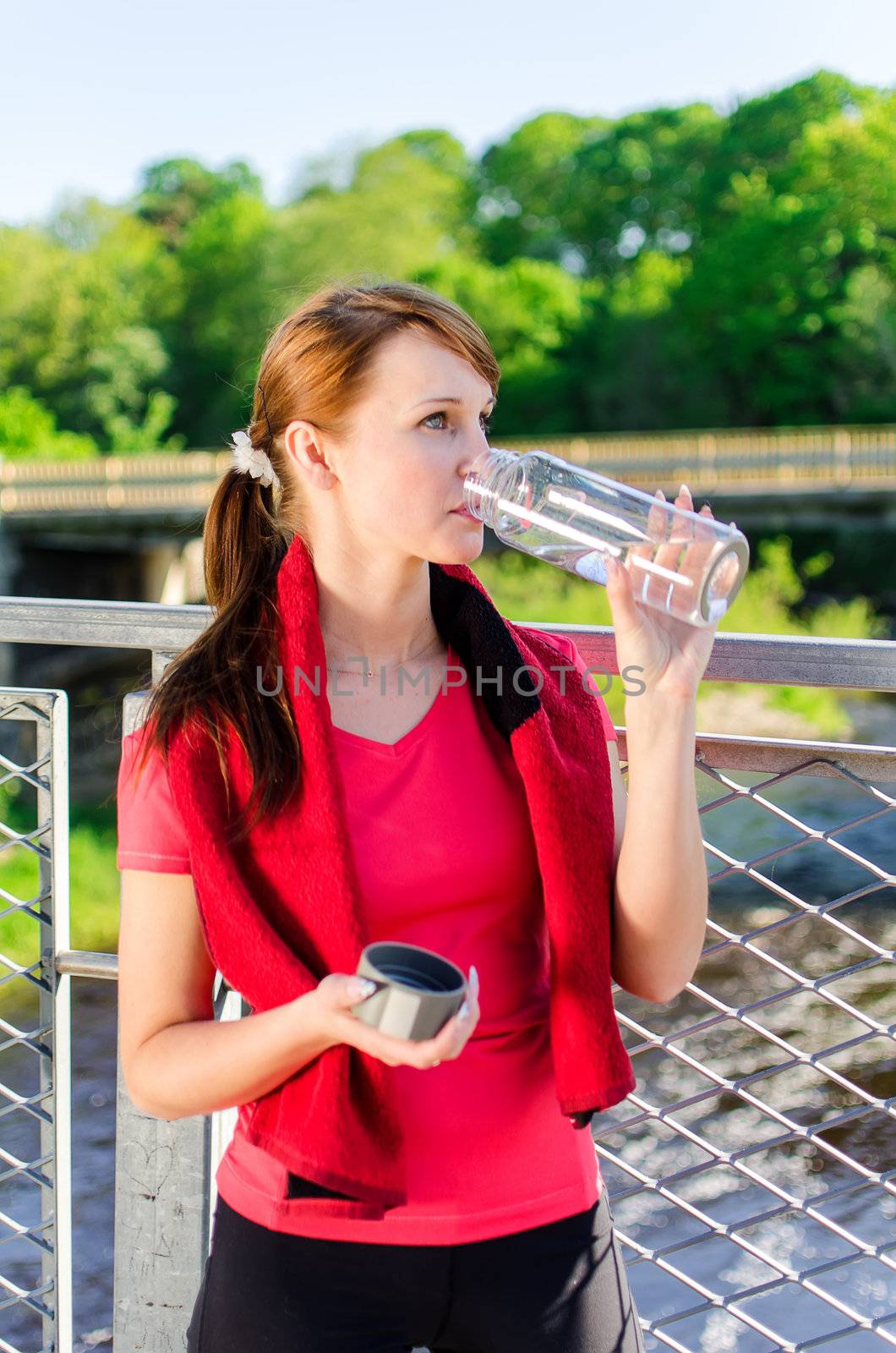Attractive woman drinking water on the bridge