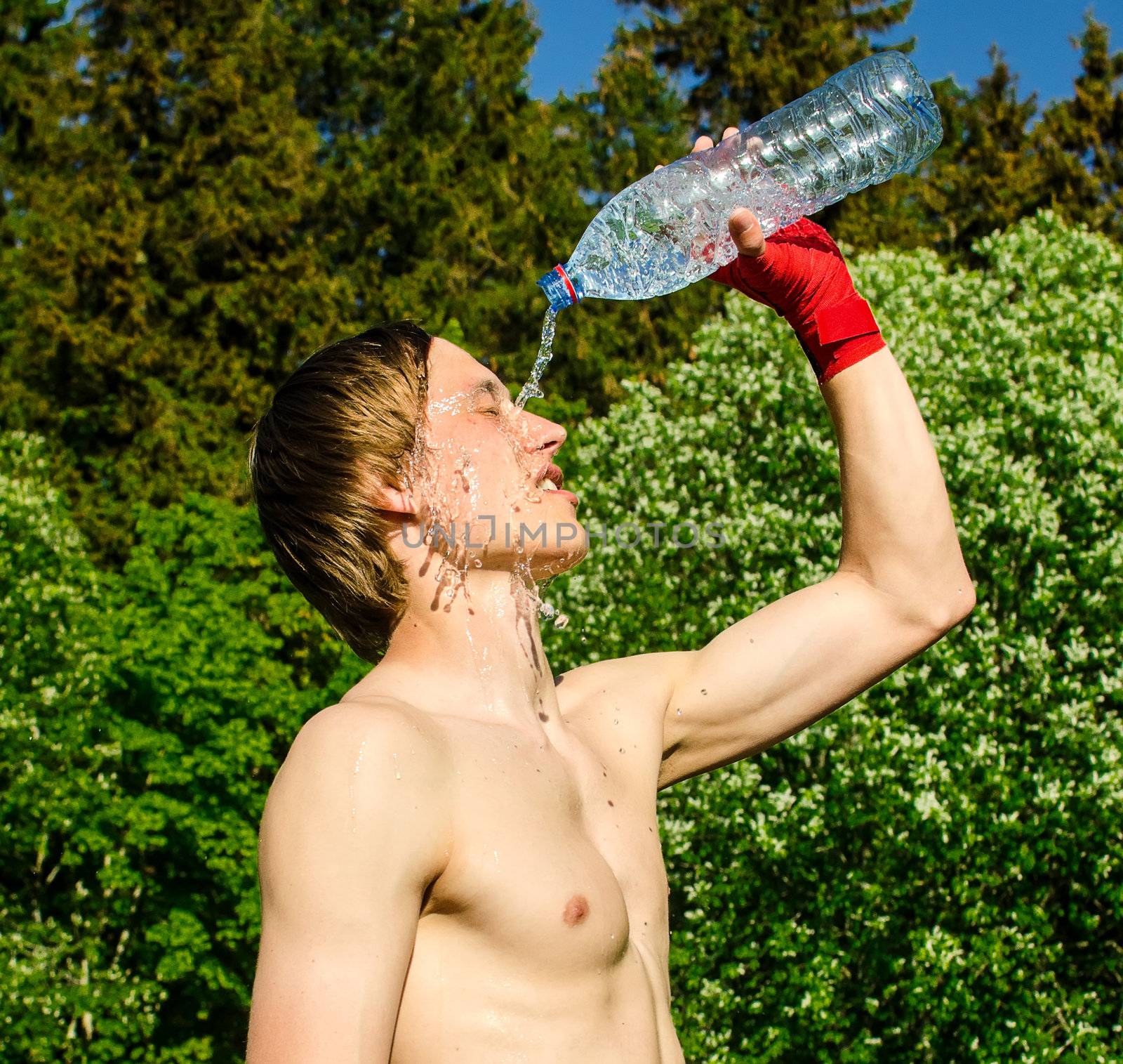 Tired sportsman pouring water on his head.