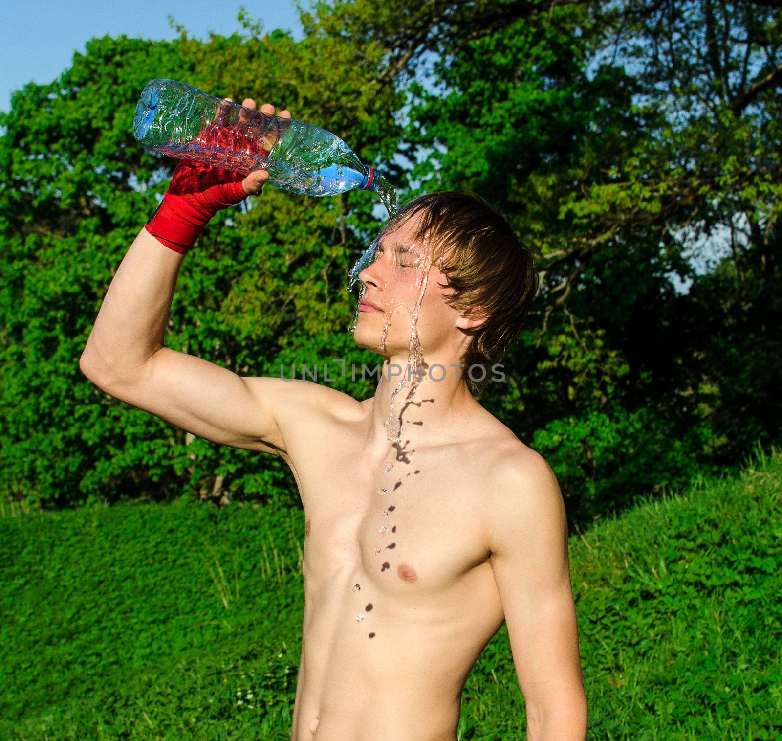 Tired sportsman pouring water on his head.