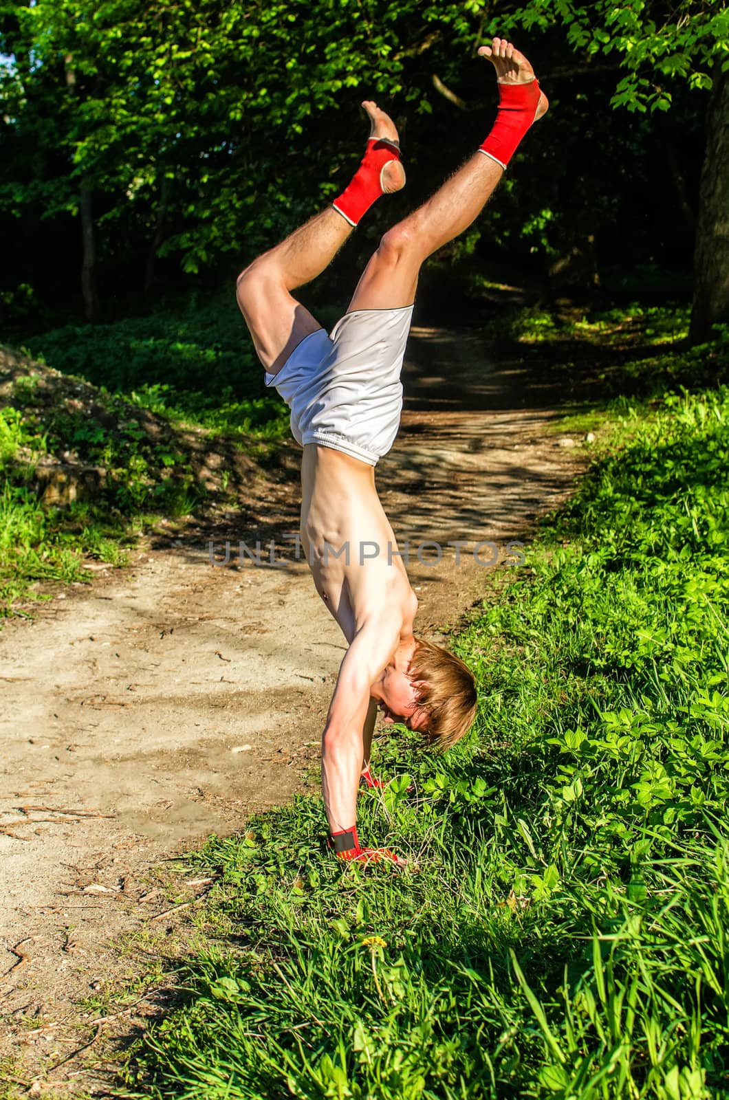 Guy stand on his hands in the forest.