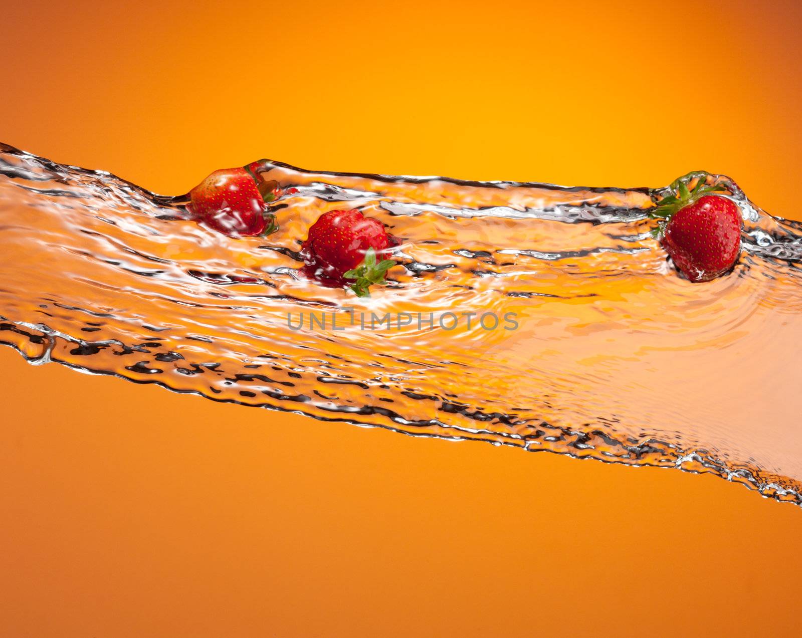 water splash with ripe red strawberry over orange background