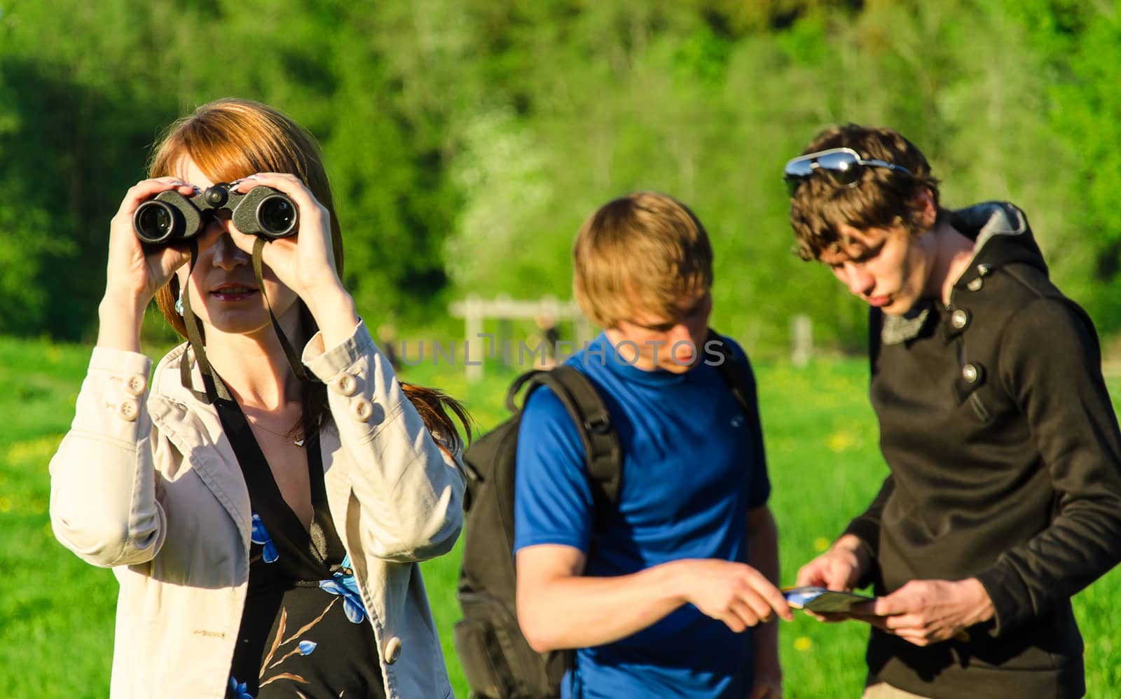 Three friends traveling. Girl looking through binoculars by dmitrimaruta