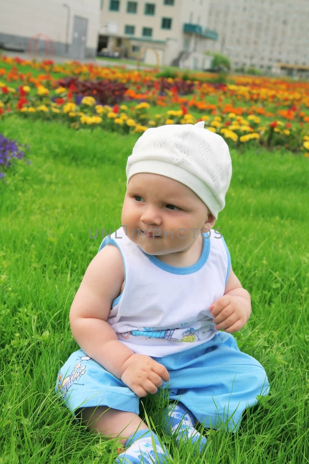 little boy with a happy kind sits on a grass