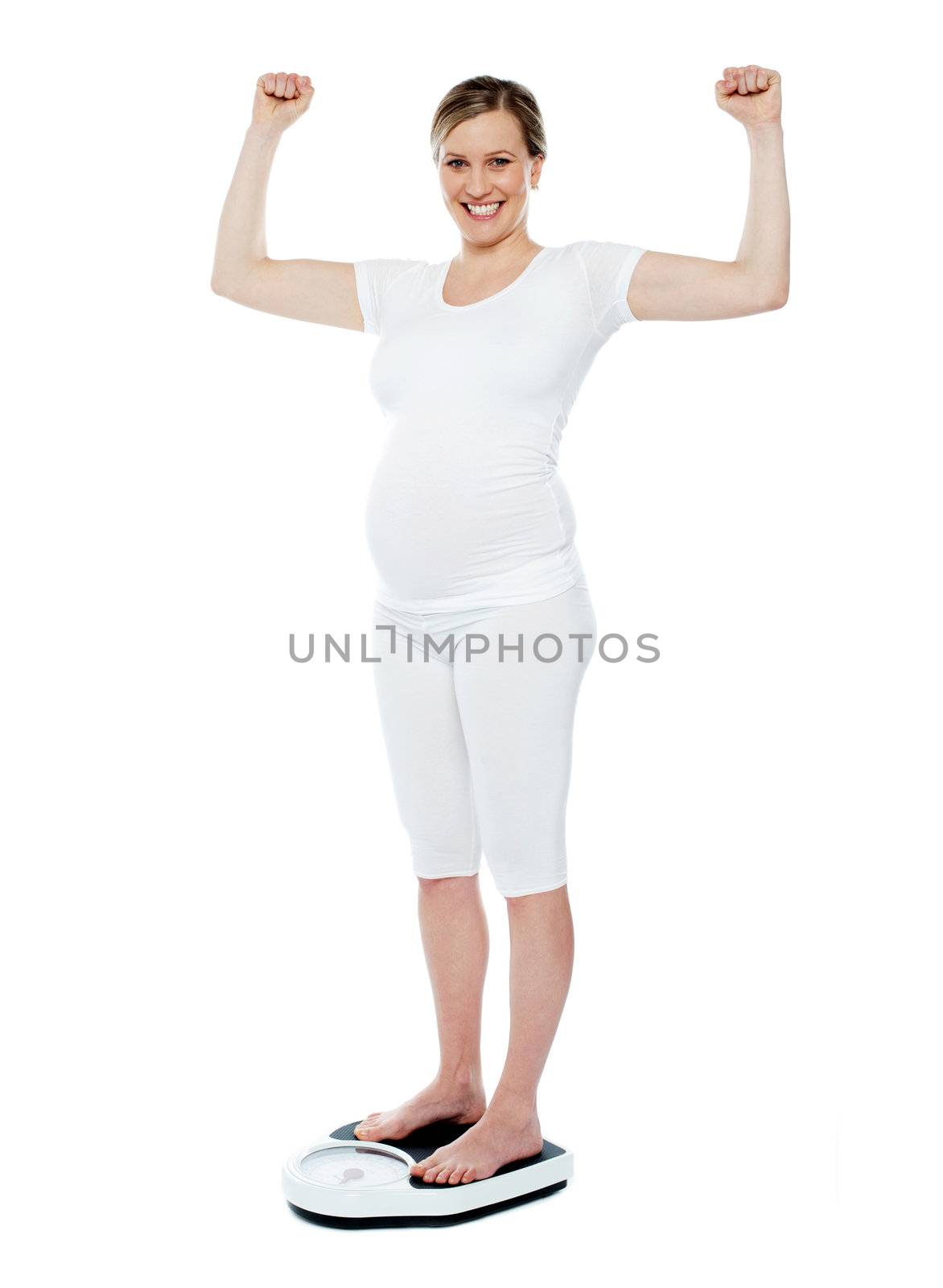 Excited pretty pregnant woman standing on weighing machine