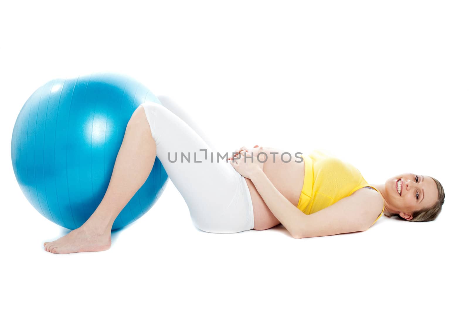 Beautiful pregnant woman lying with exercise ball by stockyimages