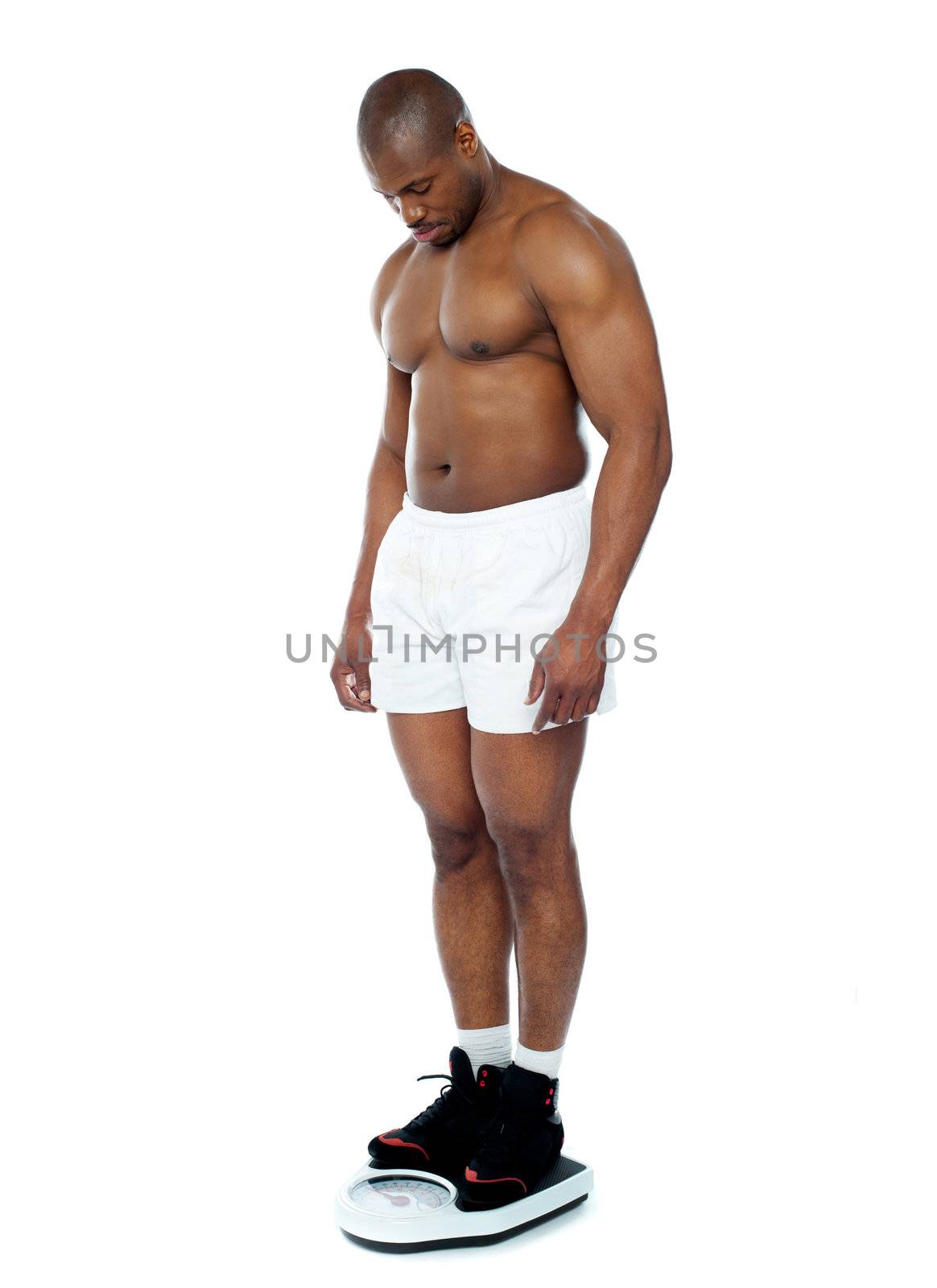 Athlete measuring his weight on weighing machine isolated over white background