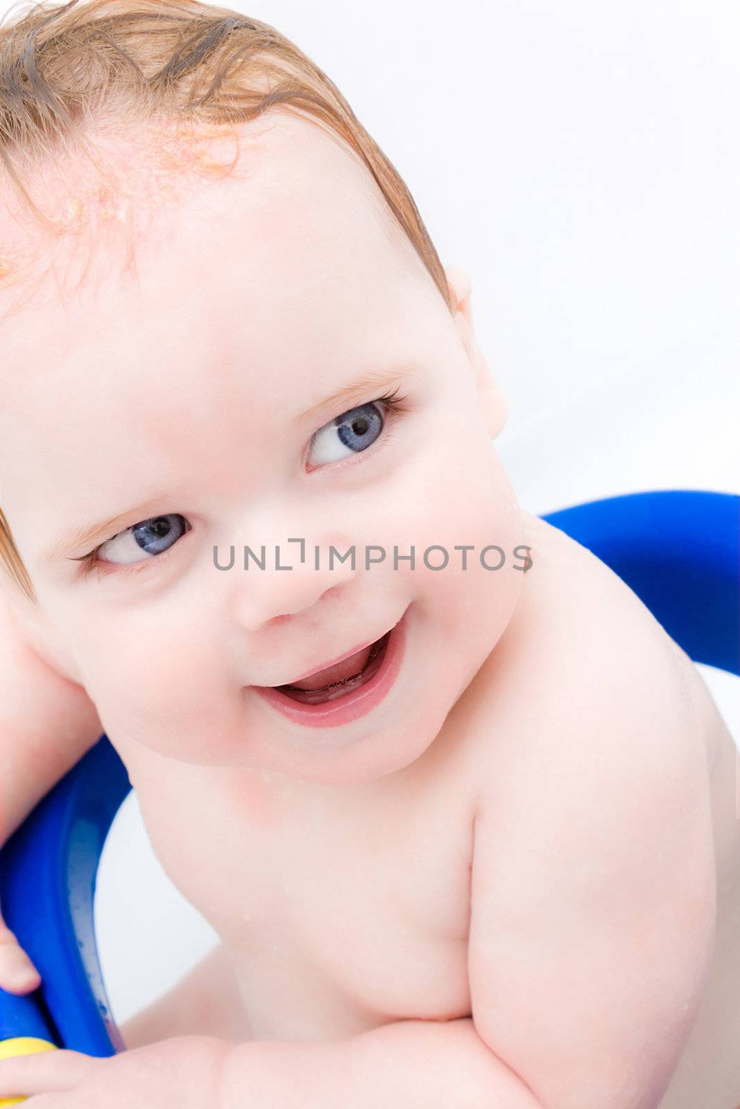 High key portrait of a young big smiled child getting cleaned in the tub