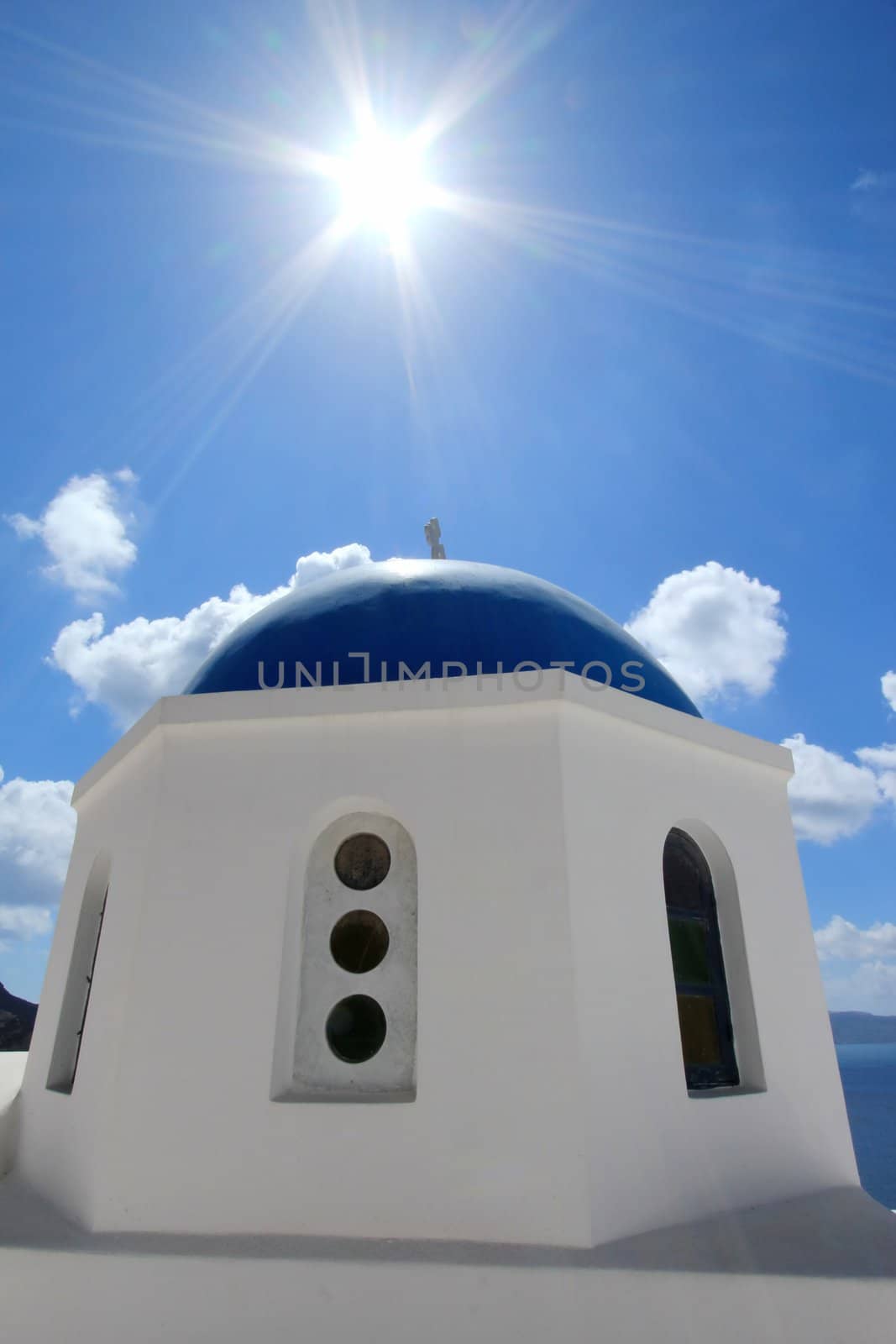 Blue dome and cross under of a greek orthodox church under the sun in Santorini island, Greece, by beautiful weather