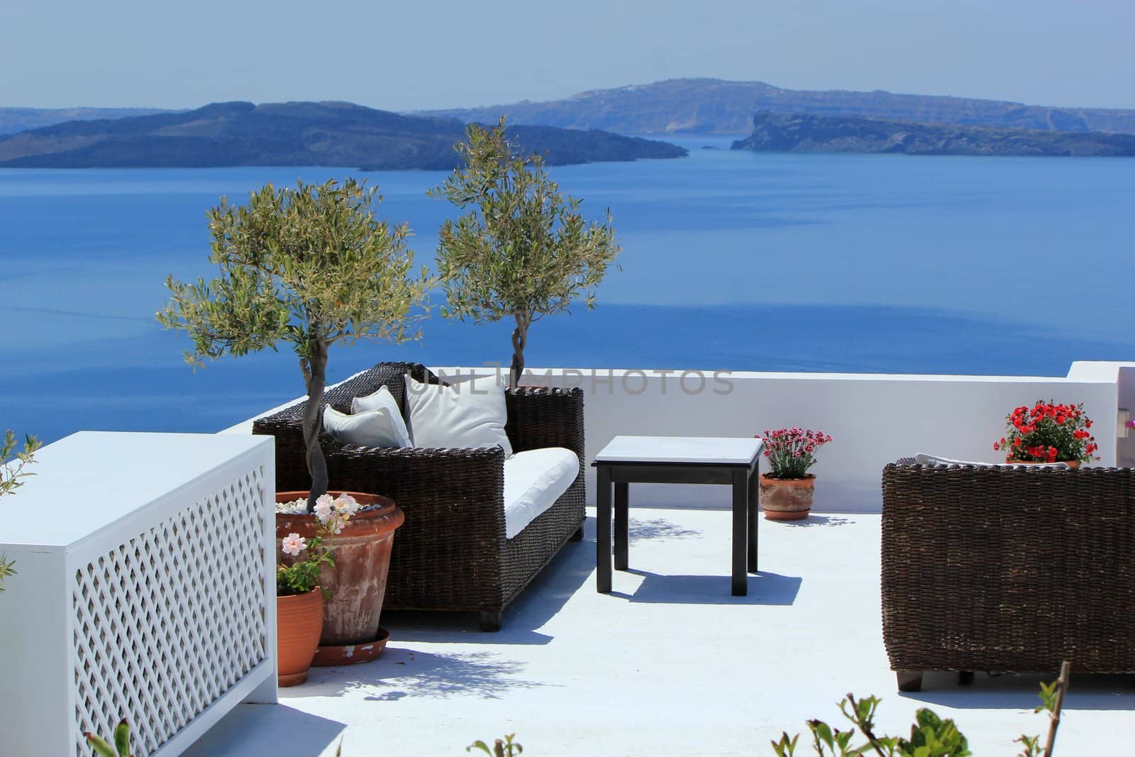 View on the volcano and Aegean sea from a balcony with furnitures at Oia, Santorini island, Greece