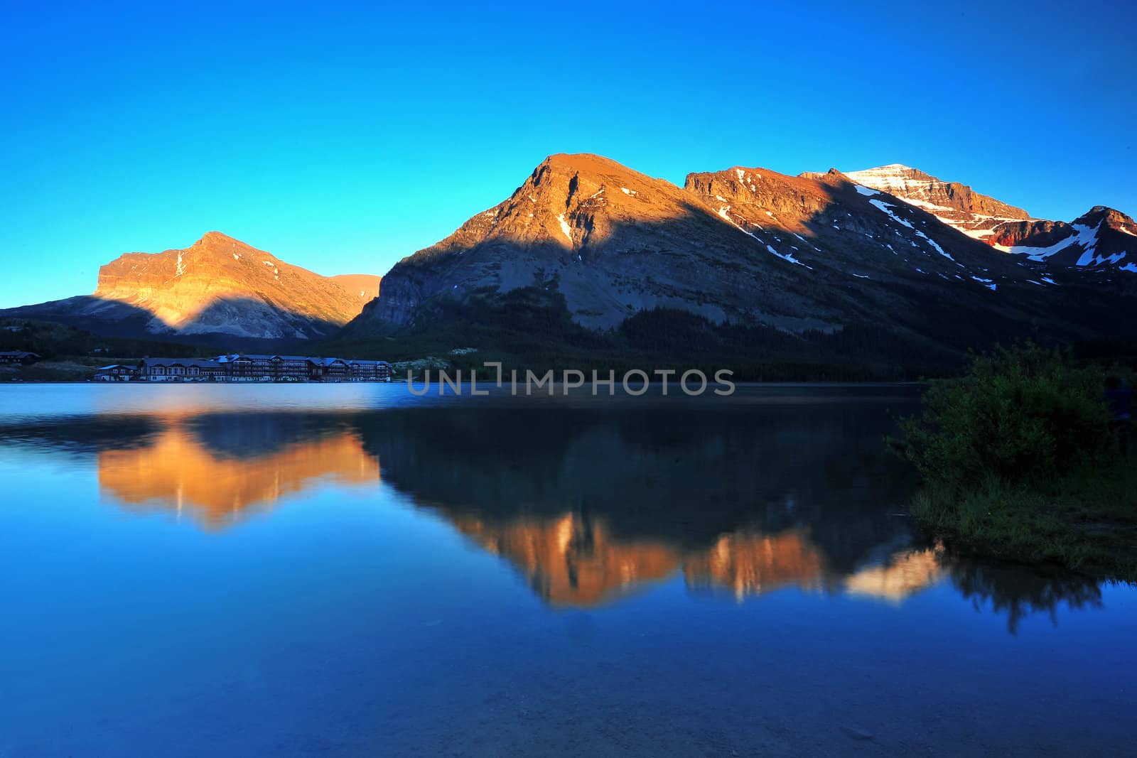 A sunset over mountains and their relections from Swiftcurrent Lake, Montana