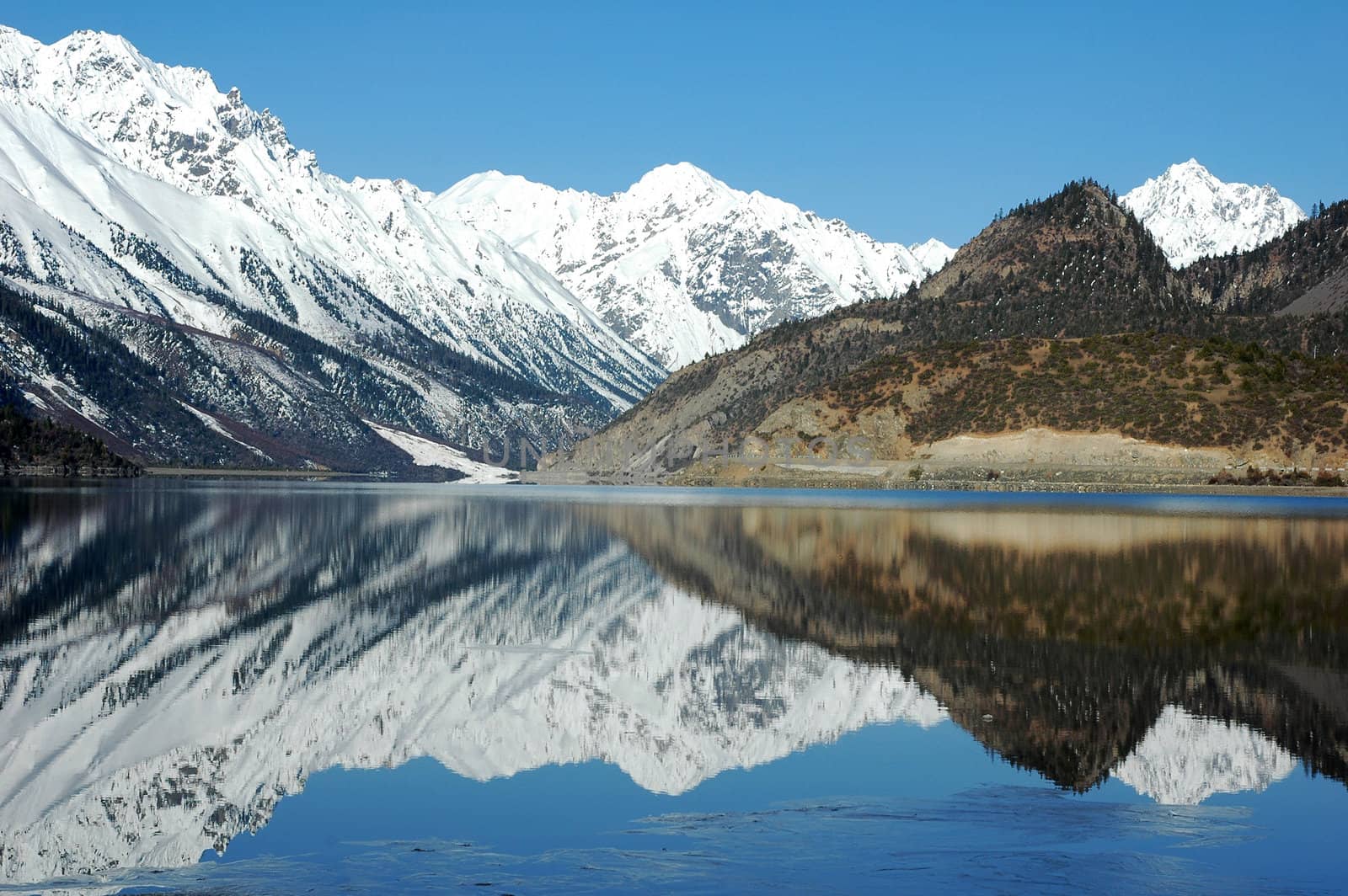 Landscape of snow-capped mountains with a mirror in the lake