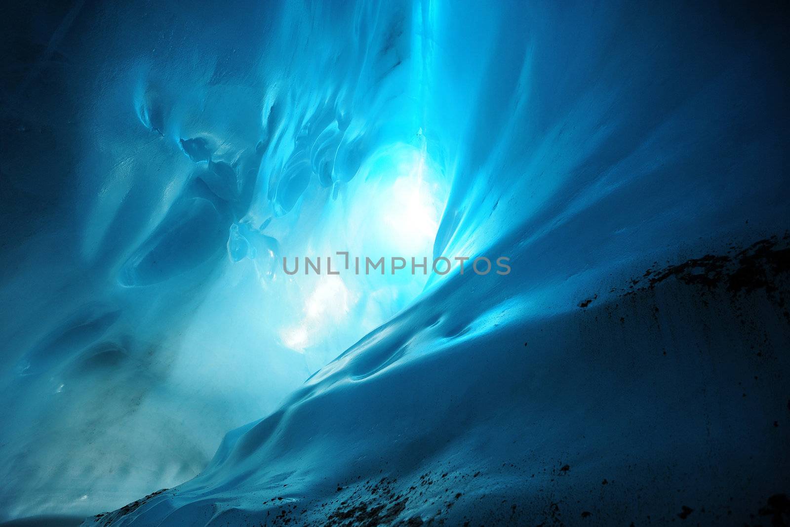 Light in a blue ice cave with curves of ice on the wall, from Root Glacier, Alaska