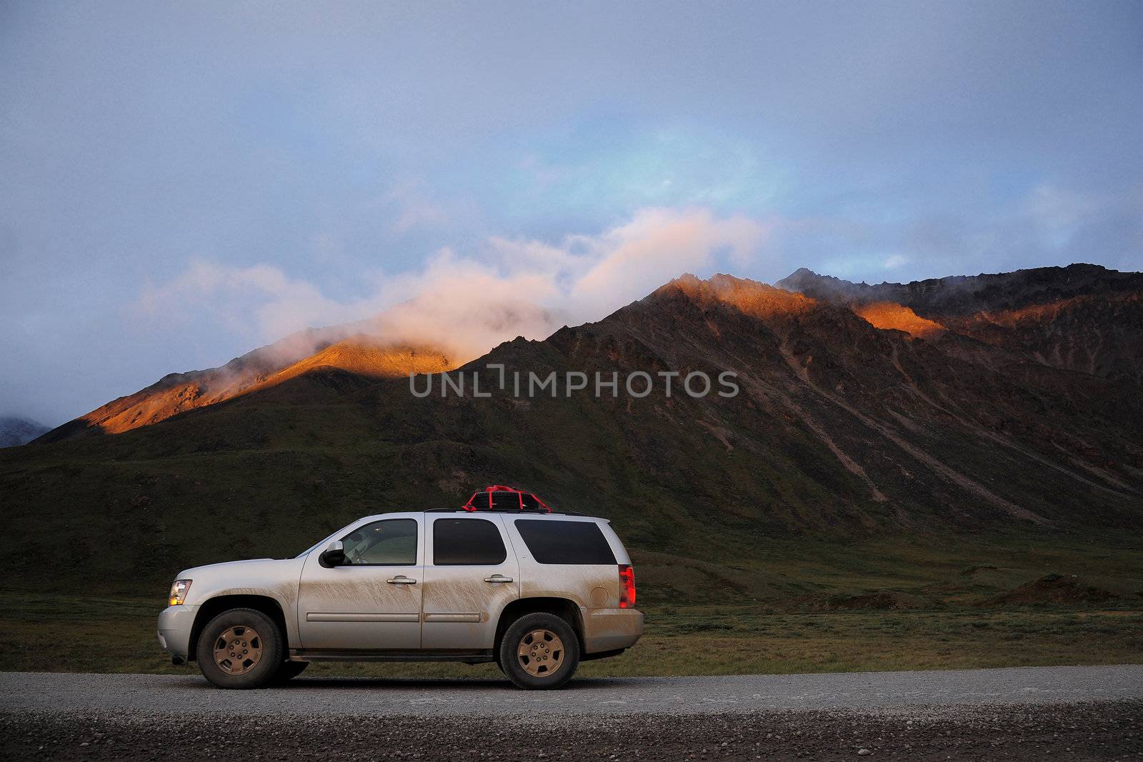 a car on unpaved Dalton Highway road from Alaska with Brook range mountain
