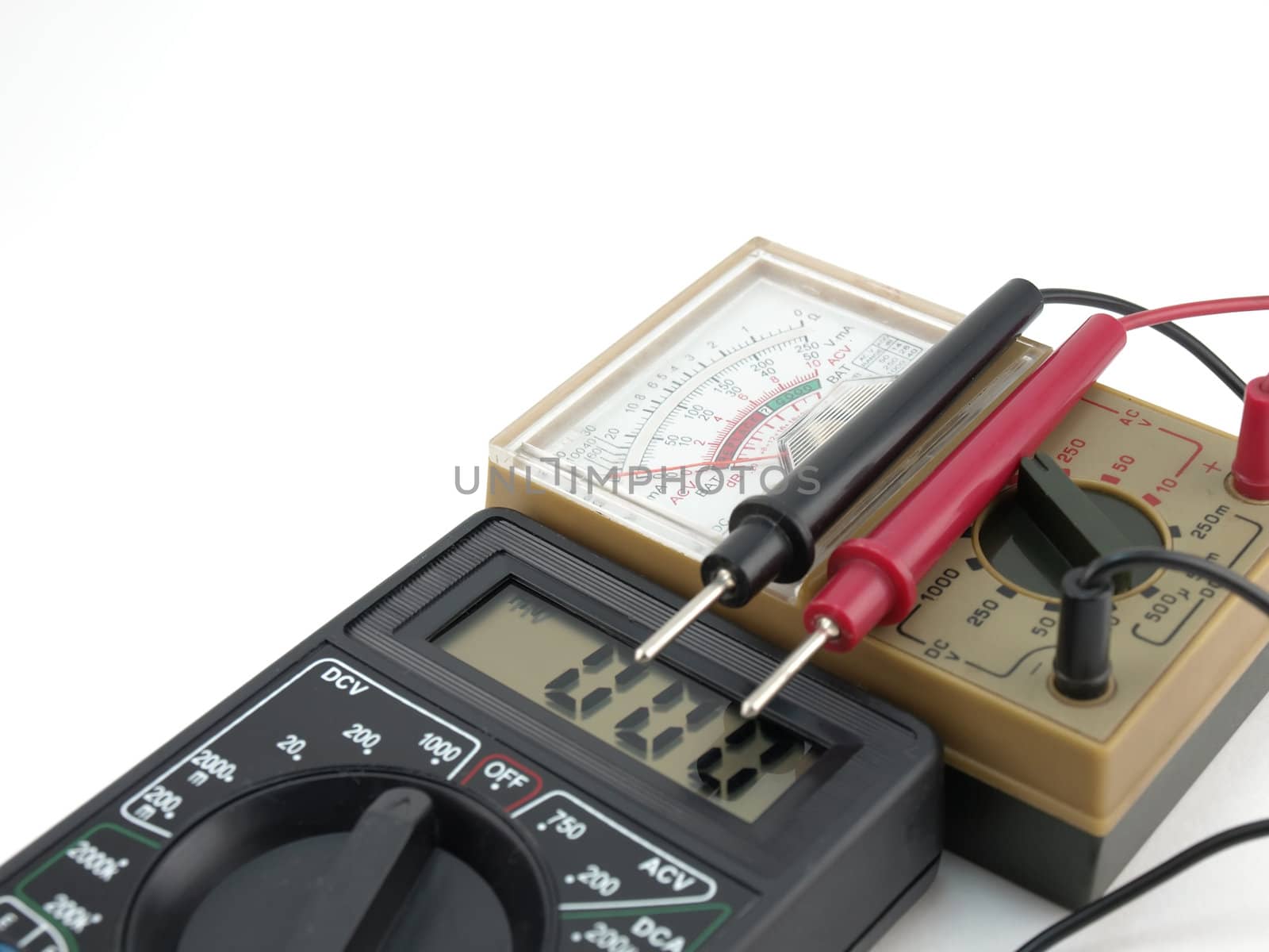 Pointer and digital multimeters over white