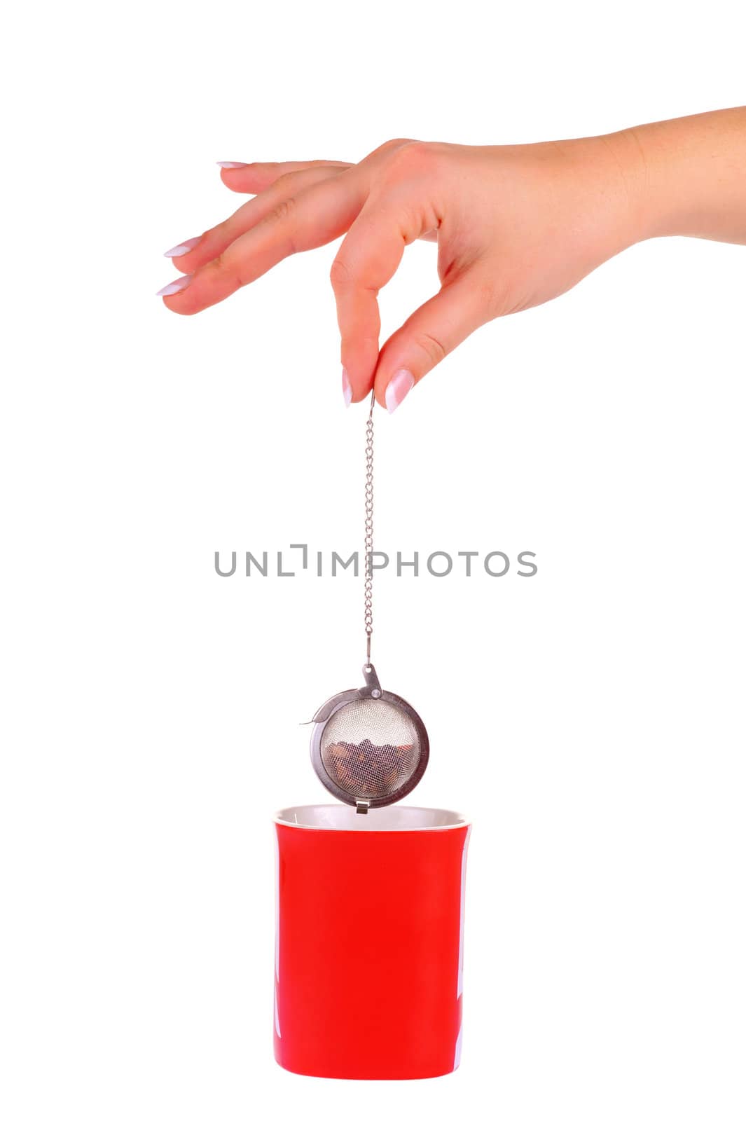 Female hand with metal tea strainer with fruit tea under red cup