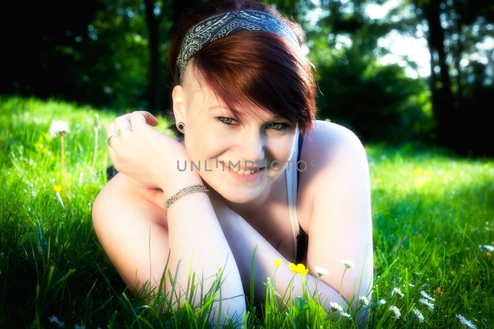 A beautiful young girl lying on the grass on a background of green 