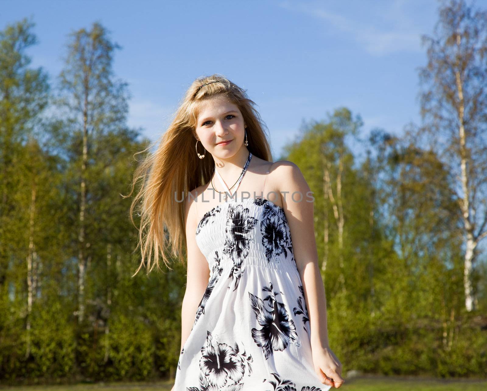 Portrait of a beautiful girl in white dress against a background of forest and blue sky