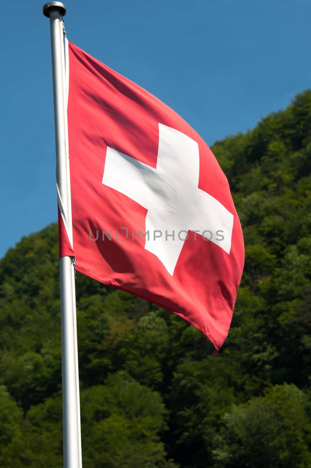 View of Switzerland countryside - swiss flag with green mountains in the background