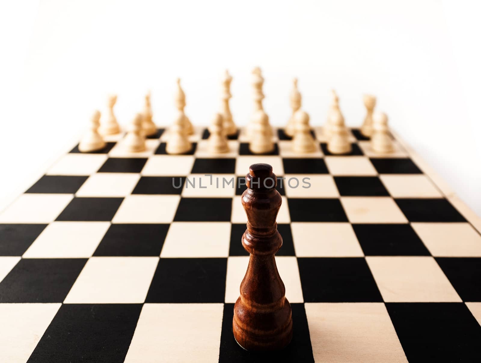 Black chess piece with a stretched perspective alone up against many white pieces. can stand for racism, challenge, adversity, diversity, courage,  or many other challenges in life.