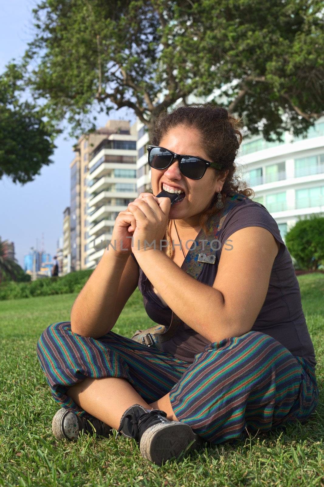 Young Peruvian Woman Biting on Mobile Phone by ildi